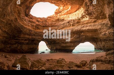 Grande grotte en pierre avec trous dans le plafond près de la mer le jour ensoleillé dans les grottes de Benagil en Algarve, Portugal Banque D'Images