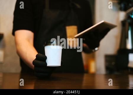 Serveur tenant une tablette à la main tout en travaillant dans un café-restaurant Banque D'Images