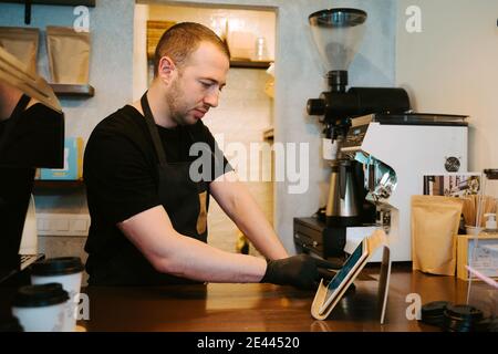 Serveur tenant une tablette à la main tout en travaillant dans un café-restaurant Banque D'Images
