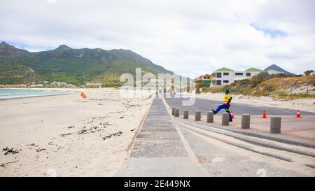 Hout Bay- Cape Town, Afrique du Sud - 19-01-2021 long parking en ciment fermé en raison d'un confinement. Un agent de sécurité portant un masque facial au premier plan. Banque D'Images