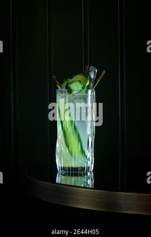 Verre de cocktail frais garni de tranches de concombre sur la table sur fond noir Banque D'Images