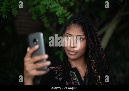 Jeune femme afro latina attrayante prenant un selfie avec un smartphone Banque D'Images