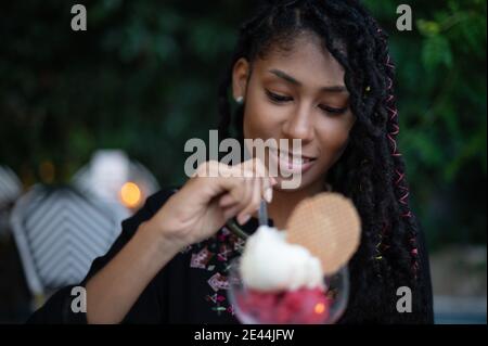 Bonne jeune femme afro latina attrayante avec des reines mangeant une glace dans un restaurant Banque D'Images