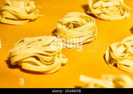 De la série ci-dessus de pâtes de fettuccine crues nids placés dessus table jaune vif Banque D'Images