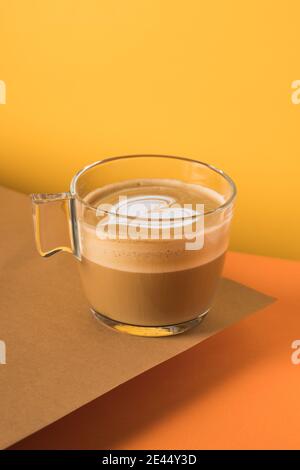 Tasse de verre de cappuccino frais et aromatique chaud avec latte art en forme de coeur servi sur la table Banque D'Images