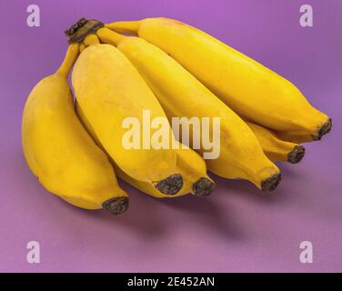 Gros plan d'un bouquet de bananes fraîches sur un arrière-plan violet Banque D'Images