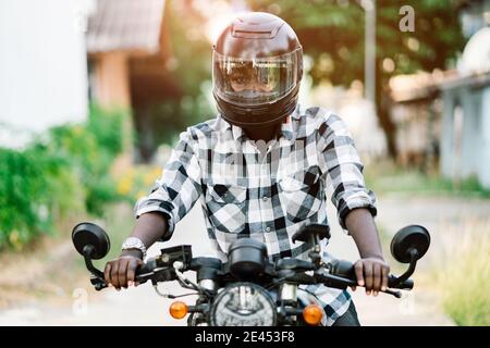 Motard africain dans le casque et les lunettes conduisant une moto manèges Banque D'Images