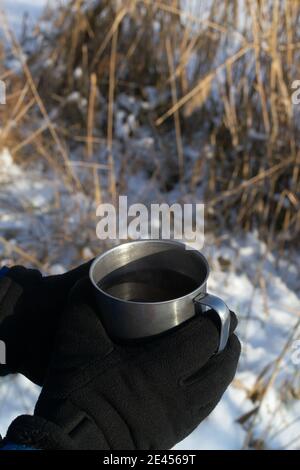 Un homme tient une tasse de thé chaud. Concept de loisirs d'hiver en plein air. Copier l'espace. Orientation verticale. Banque D'Images