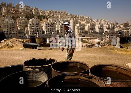 Le palestinien Saeid Eid se trouve à côté de sa maison, non vu, alors que la construction se poursuit sur un nouveau développement de logements dans le quartier juif de Har Homa à Jérusalem-est, en arrière-plan, le mercredi 3 juin 2009. Le Premier ministre israélien Benjamin Netanyahou subit une forte pression américaine pour remettre le processus de paix sur la bonne voie en reconnaissant le droit des Palestiniens à un état qui leur est propre et en mettant un terme à l'expansion des colonies en Cisjordanie. Photo par Olivier Fitoussi/ABACAPRESS.COM Banque D'Images