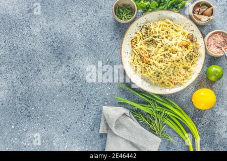 Pâtes linguine aux champignons, crevettes et moules de fruits de mer, fromage et herbes, en plaque de céramique sur une surface gris clair. Banque D'Images