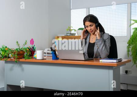 Gros plan d'une jeune femme attirante travaillant avec un casque au bureau Banque D'Images