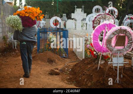 Vendeur de fleurs marchant dans le cimetière pendant le jour des morts Banque D'Images