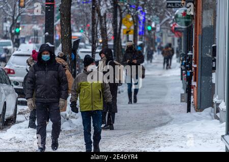 Montréal, CA - 21 janvier 2021 : piétons avec masques pour la protection contre la COVID-19 marchant dans la rue pendant la tempête de neige Banque D'Images