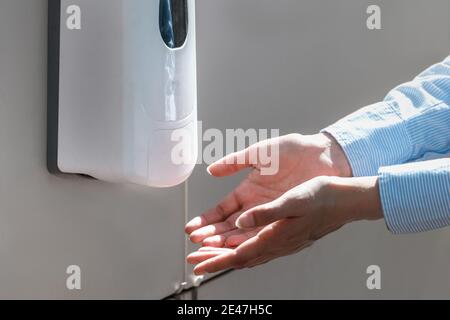 Gros plan des mains de la femme et de l'assainisseur dans un endroit public. Banque D'Images