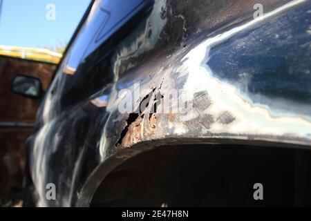 Corrosion du métal sur l'aile d'une voiture, trou de rouille. Réparation de la carrosserie d'une voiture. Vue latérale. Banque D'Images