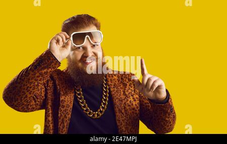 Joyeux jeune homme riche barbu avec collier de chaîne d'or pointant finger et sourire Banque D'Images