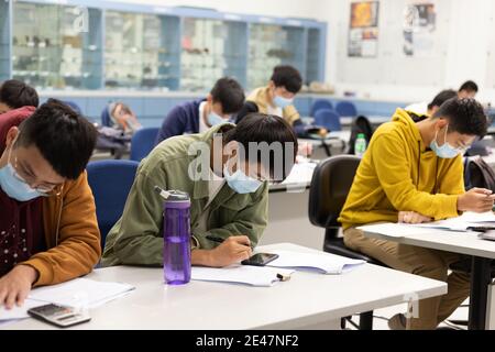 22 01 2021 élèves de sexe masculin et féminin qui suivent des cours ou travail de papier dans la salle de classe avec masque de visage dans l'université dans Hong Kong pendant Covid-19 Banque D'Images