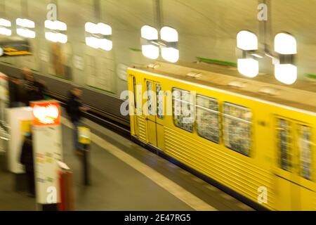 Un train de métro jaune qui accélère dans une station animée, capturant le rythme effréné des déplacements urbains. Banque D'Images