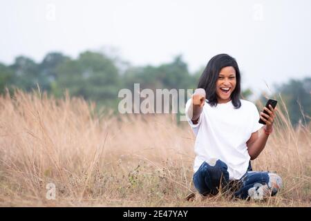 belle femme africaine se sentant heureuse et excitée en l'utilisant le téléphone pointe vers l'avant de la caméra Banque D'Images