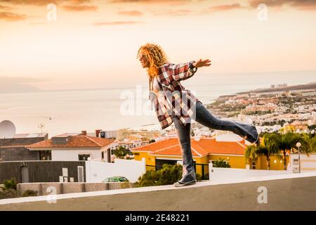 Concept de bonheur et de liberté pour une jeune femme indépendante et belle marchant équilibré sur un mur avec la ville et la côte de mer dedans contexte - vacances d'été Banque D'Images