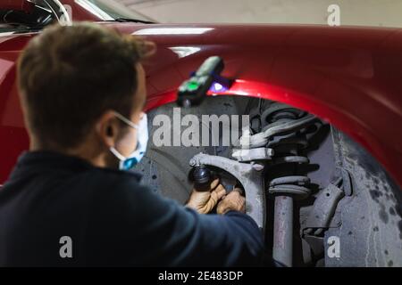 mécanicien répare la suspension de voiture. Concentrez-vous sur les mains. COVID 19 Banque D'Images