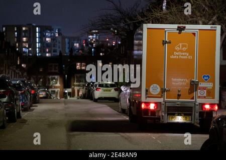 Une fourgonnette de livraison Sainsbury dépose un bon de commande en ligne pour les clients qui vivent dans une rue résidentielle sombre de Herne Hill, dans le sud de Londres, le 21 janvier 2021, à Londres, en Angleterre. Banque D'Images