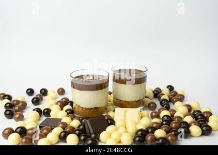 Deux desserts au chocolat en verre (yaourt ou crème, biscuits et noix) avec des boules de chocolat (chocolat noir, chocolat au lait et chocolat blanc). Bonbons Banque D'Images