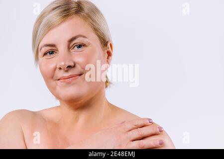 Une photo agrandie d'une femme plus âgée avec un sourire doux et une peau pure et naturelle sur un fond blanc avec un espace latéral. Banque D'Images