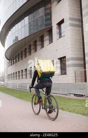 Vue arrière d'un messager portant un sac à dos thermo, faisant du vélo en ville Banque D'Images