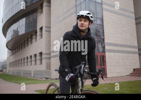 Jeune homme portant un casque de vélo tout en faisant du vélo dans les rues de la ville Banque D'Images