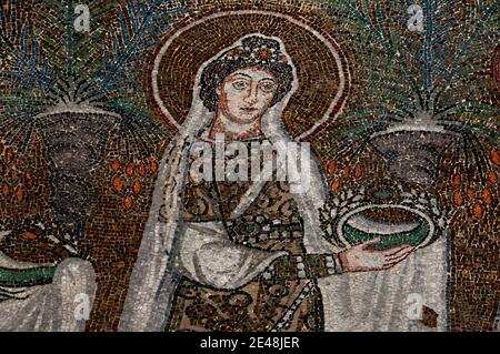L'une des 22 saintes chrétiennes somptueusement habillées dans une tiare ornée de bijoux et tenant une couronne ou une couronne ornée de bijoux marche en procession. Détail de la mosaïque byzantine, créée dans les années 500 après JC, dans la Basilique di Sant’Apollinare Nuovo à Ravenne, Emilie-Romagne, Italie. Banque D'Images