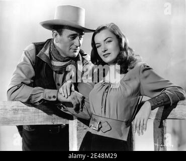 JOHN WAYNE et ELLA RAINES Publicité Portrait par ERNEST A. BACHRACH en HAUT DANS LA SELLE 1944 réalisateur EDWARD L. MARIN Histoire originale Gordon Ray Young scénario Michael Hogan et Paul Fix RKO radio Pictures Banque D'Images