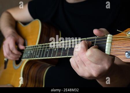 Une main mâle tout en jouant une guitare électro-acoustique. Gros plan. La main humaine joue de la guitare. École de guitariste. École de guitariste. Banque D'Images