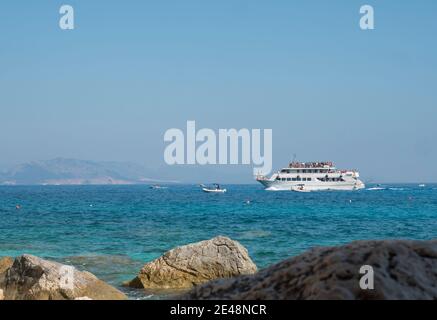 Cala Goloritze, Sardaigne, Italie, 8 septembre 2020: Une vue de bateau de croisière touristique à l'eau turquoise du golfe d'Orosei vu de la côte rocheuse. Banque D'Images