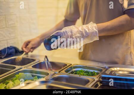 L'homme cuisine le porc vietnamien Banh mi Sandwich in une baguette noire Banque D'Images