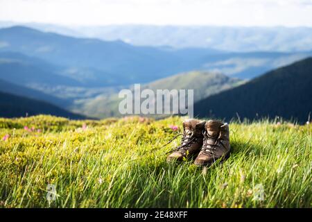 Bottes de tourisme solitaire sur une colline de montagnes couvertes d'herbe luxuriante. Photographie de paysage Banque D'Images