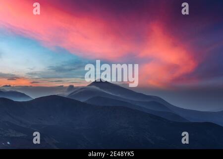 Vue de l'herbe des collines dans les Carpates par soir rougeoyant du soleil. Le ressort dramatique scène. Photographie de paysage Banque D'Images