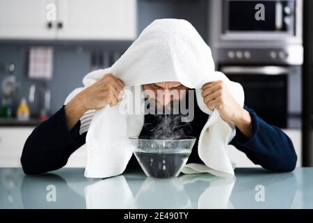 Homme faisant l'inhalation alternative de la médecine de fines herbes à l'aide du bol à vapeur Banque D'Images