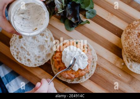 Une femme qui dégusterait une sauce tartare maison sur un saumon et hamburger aux crevettes Banque D'Images