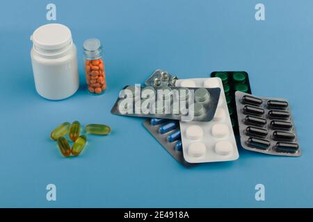 Tas de pilules dans l'emballage de blister et la bouteille en plastique se trouve sur le bureau bleu. Concept de soins de santé, toxicomanes ou armes chimiques. Banque D'Images