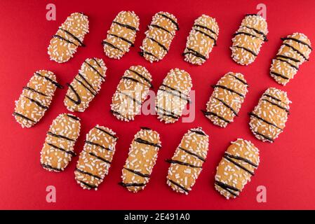 Biscuit avec des grains de sucre et des bandes de chocolat, ladyfingers italiens appelés Tresor sur fond rouge, vue de dessus, couche plate Banque D'Images