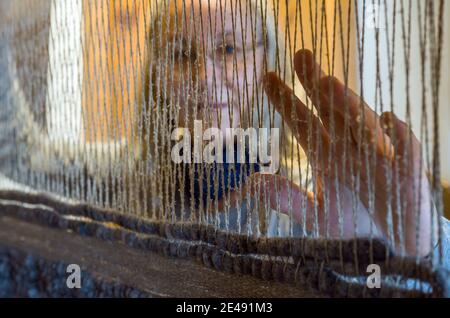 07 janvier 2021, Brandebourg, Batzlow: Constanze Büxler, propriétaire d'Urticahof, peut être vu faiblement derrière des fils sur un métier à tisser. Au milieu de Märkische Schweiz, les tapis et les tissus sont fabriqués selon les spécifications du client sur les métiers à main. Dans les cours, les visiteurs peuvent apprendre le feutrage, le spinning ou la teinture avec des matériaux naturels. Les anciennes techniques artisanales sont fascinantes, mais elles ne sont plus rentables. Photo: Patrick Pleul/dpa-Zentralbild/ZB Banque D'Images