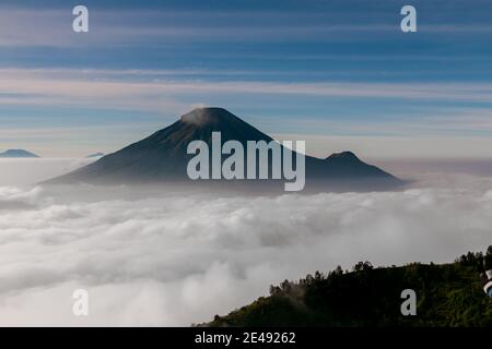 Vue sur les montagnes de Sindoro avec une mer de ​​clouds dans le centre de Java, Indonésie du haut tôt le matin Banque D'Images