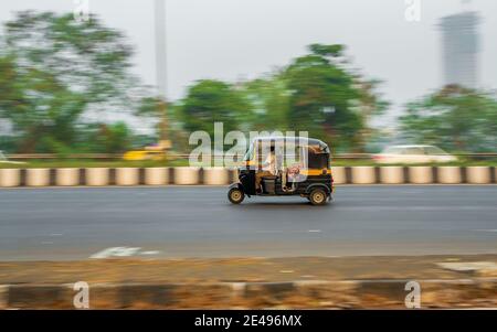 MUMBAI, INDE - 17 décembre 2020 : conducteur de tuk-tuk non identifié portant un masque de protection contre Covid-19 et conduisant de célèbres pousse-pousse noir et jaune, Banque D'Images