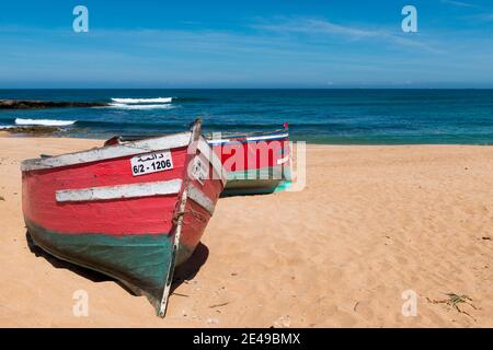 El Jadida, Maroc - 16 avril 2016 : deux bateaux de pêche traditionnels colorés sur une plage près de la ville d'El Jadida, sur la côte atlantique du Maroc. Banque D'Images