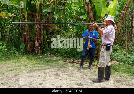 Homme utilisant un long pistolet à air; pratique; observation de l'homme indigène; jungle; bottes en caoutchouc, arme, chasse, peinture faciale, Amérique du Sud, Amazon Tropical Rain Banque D'Images