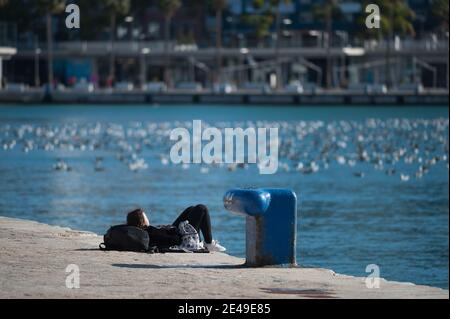 Malaga, Espagne. 22 janvier 2021. Un jeune qui se repose sur le côté de la promenade à Muelle Uno dans le cadre d'une pandémie de coronavirus.la région d'Andausia souffre d'une augmentation quotidienne incontrôlée des cas de coronavirus, malgré les restrictions sévères imposées dans la vie quotidienne. Au cours des dernières semaines, l'Andalousie a signalé des milliers d'infections chaque jour dans la région tandis que la pression hospitalière continue d'augmenter. Crédit : SOPA Images Limited/Alamy Live News Banque D'Images