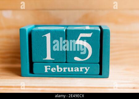 Février 15. Calendrier cube bleu avec mois et date sur fond en bois. Banque D'Images