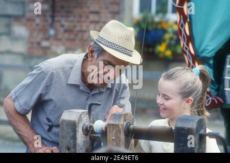 1990 Tourneurs de démonstration - UN homme faisant la démonstration de Tourneurs sur un tour de pied de treddle à une jeune fille à Rufford Abbey Country Park, Notinghamshire. Les tours en bois fonctionnent avec une révolution alternative ou continue.les Tourneurs sont l'art d'utiliser le tour en bois avec des outils à main pour couper une forme qui est symétrique autour de l'axe de rotation. L'opérateur est connu sous le nom de turner, et les compétences nécessaires pour utiliser les outils étaient traditionnellement connues sous le nom de turnery. Homme poteau tour tournant Rufford Abbey Country Park Notinghamshire Angleterre GB Royaume-Uni Europe Banque D'Images