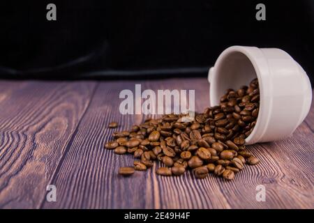 Un grain de café arrosé d'une tasse blanche sur un table en bois Banque D'Images